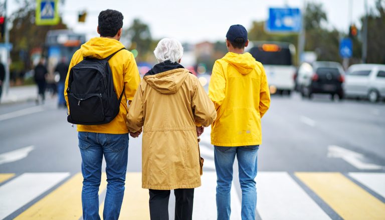 Senior lady and two young men dressed in yellow raincoats, standing in the middle of the street - like a sitting duck