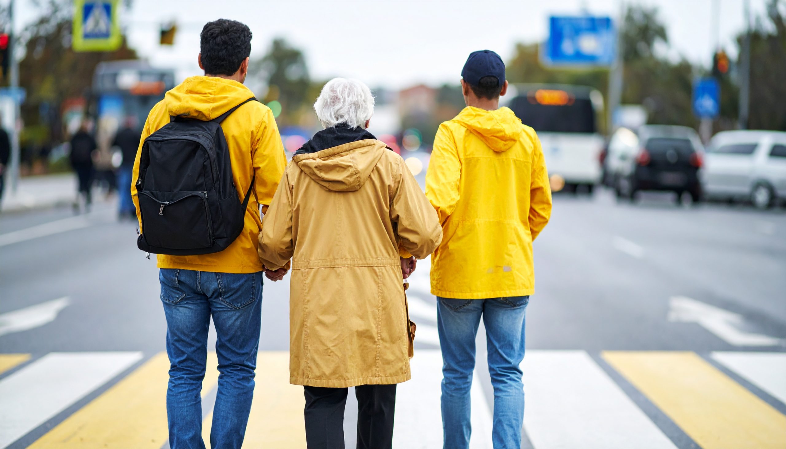 Senior lady and two young men dressed in yellow raincoats, standing in the middle of the street - like a sitting duck